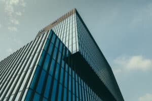 Immeuble moderne vitré contre ciel bleu.