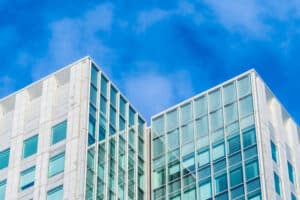 Façade en verre d'immeuble moderne contre ciel bleu.