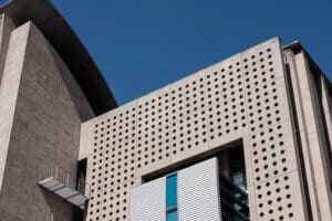 Façade moderne en béton perforé sous ciel bleu.