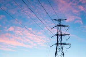 photo d'un pylône électrique avec des lignes électriques et un fond ciel bleu et rose